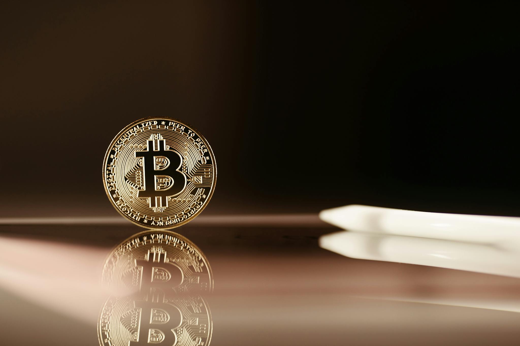 A close-up image of a Bitcoin coin reflecting on a shiny surface, highlighting cryptocurrency themes.